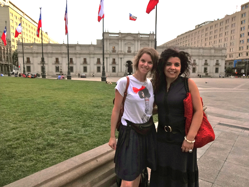 Karen Ranke mit Freundin in Santiago de Chile vor einem historischen Gebäude, davor wehen Flaggen an Fahnenmasten im Wind