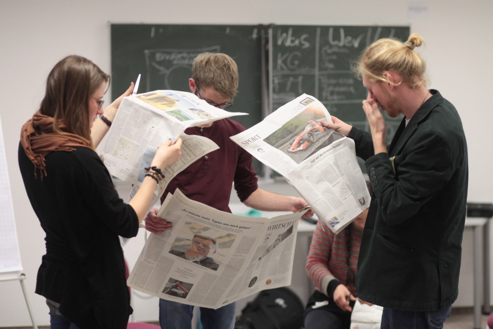 kulturweit-Freiwillige lesen Zeitung in einem Seminarraum.