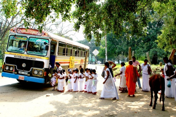 Straßenszene in Battaramulla, viele in weiß gekleidete Kinder stehen vor einem gelben Bus